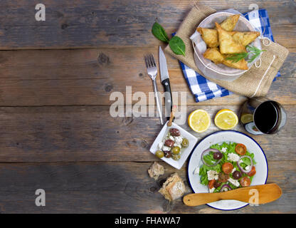 Feta-Käse und Spinat Blätterteig-Gebäck und griechischer Salat auf einem Holztisch gelegt Stockfoto