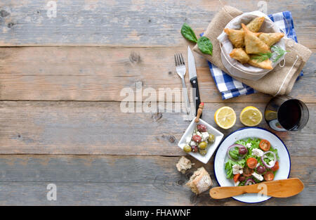 Feta-Käse und Spinat Blätterteig-Gebäck und griechischer Salat auf einem Holztisch gelegt Stockfoto