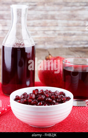 Frische reife Granatäpfel und Saft in das Glas auf roter Serviette Stockfoto