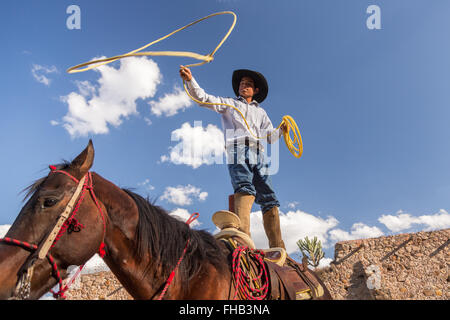 Eine mexikanische Charro oder Cowboy Praktiken Abseilen Fähigkeiten auf seinem Pferd vor einem Charreada Wettkampf auf einer Hacienda-Ranch in Alcocer, Mexiko. Die Charreada ist eine traditionelle mexikanische Rodeo und testet die Fähigkeiten des Cowboys reiten, Abseilen und Vieh zu kontrollieren. Stockfoto