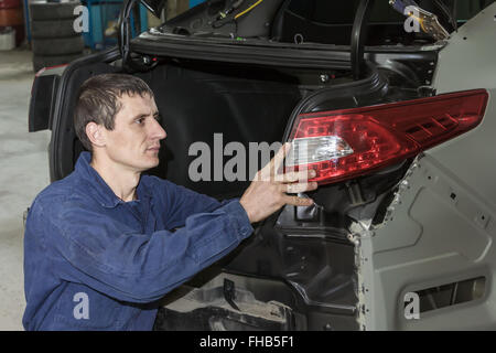 Junge Mechaniker installiert Rücklicht am Fahrzeug. Stockfoto