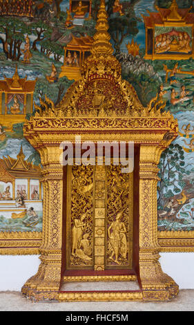 Kunstvoll geschnitzte Tür und Wandmalereien auf einen buddhistischen Tempel - LUANG PRABANG, LAOS Stockfoto