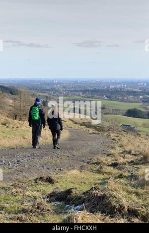 Ein junges Paar zu Fuß in die Old Kilpatrick Hügel mit Blick auf Glasgow, Scotland, UK, an einem feinen Wintertag. Stockfoto