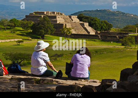 Touristen sehen SYSTEM IV Gebäude K einen Tempel im GRAND PLAZA am MONTE ALBAN ZAPOTEKEN Stadt 500 BC - OAXA stammt Stockfoto