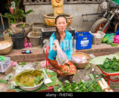 Lao Mädchen verkaufen Klebreis in Bananenblättern am Wochenmarkt in Luang Prabang Laos gewickelt Stockfoto