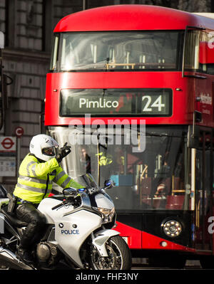 Polizei-Motorradfahrer hält Verkehr in Whitehall London mit Bus Nummer 24 to Pimlico im Hintergrund Stockfoto