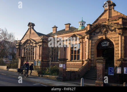 Eine Mutter führt ihre Kinder vorbei an der äußeren Fassade der Carnegie-Bibliothek in Herne Hill. Konfrontiert mit der Schließung der örtlichen Bibliothek, Lambeth Rates Plan, in der Nähe der Anlage wird von der Gemeinschaft im Rahmen der Sparmaßnahmen, die sagen, dass sie das Gebäude in ein Fitness-Studio und Privatbesitz gentrifizierten Unternehmen - anstatt eine beliebte Lektüre und Lernressource zu konvertieren. £12.600 wurde von der amerikanischen Philanthrop Andrew Carnegie zum Aufbau die Bibliothek im Jahre 1906 eröffneten gestiftet. Stockfoto