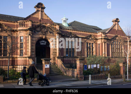 Eine Mutter führt ihre Kinder vorbei an der äußeren Fassade der Carnegie-Bibliothek in Herne Hill. Konfrontiert mit der Schließung der örtlichen Bibliothek, Lambeth Rates Plan, in der Nähe der Anlage wird von der Gemeinschaft im Rahmen der Sparmaßnahmen, die sagen, dass sie das Gebäude in ein Fitness-Studio und Privatbesitz gentrifizierten Unternehmen - anstatt eine beliebte Lektüre und Lernressource zu konvertieren. £12.600 wurde von der amerikanischen Philanthrop Andrew Carnegie zum Aufbau die Bibliothek im Jahre 1906 eröffneten gestiftet. Stockfoto