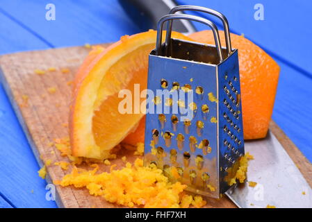 Orange Frucht und Orangenschale mit Reibe auf Holzbrett Stockfoto