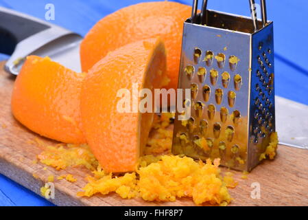 Orange Frucht und Orangenschale mit Reibe auf Holzbrett Stockfoto