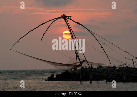 Chinesische Fischernetze Silhouette durch den Sonnenuntergang am Strand von Cherai, Vypin Insel in Kerala, Indien Stockfoto