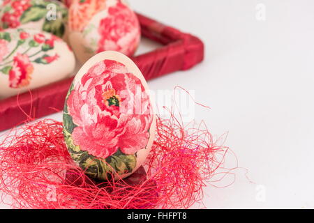 Serviettentechnik dekoriert Easter Egg auf roten Stroh Stockfoto