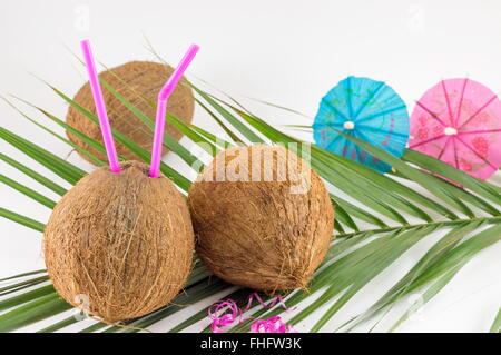 Frische Kokosnuss Cocktails mit Sonnenschirmen auf Kokosnussblättern platziert Stockfoto