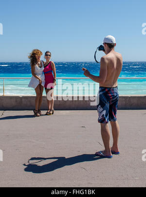 Junger Mann Fotografieren von zwei jungen Damen im Urlaub am Meer Stockfoto