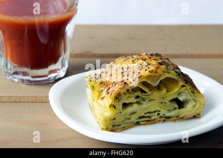 Spinat und Käse Kuchen mit einem Glas Tomatensaft auf einem Holztisch Stockfoto