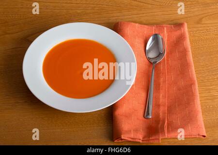 Einfaches Bild einer Schüssel Suppe mit einem Löffel und Serviette auf einem Holz Küchentisch genommen von oben Stockfoto