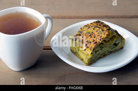 Spinat und Käse Kuchen mit einer Tasse Tee auf einem Holztisch Stockfoto