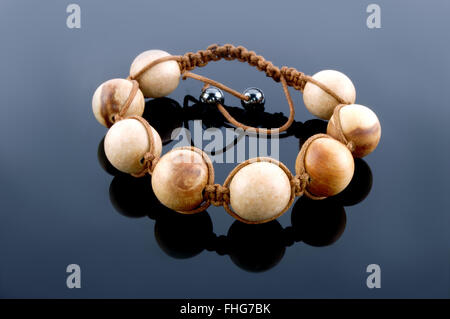 Shamballa Armband aus Holz auf einem schwarzen Hintergrund gespiegelt Stockfoto