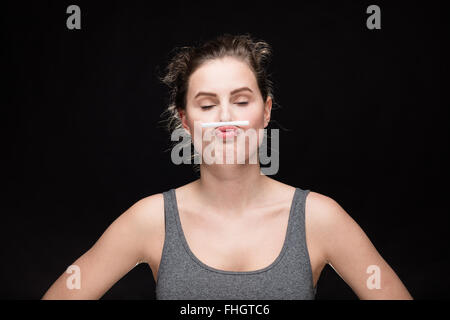 junge Frau mit Zigarette Schnurrbart, Rauchen Konzept auf schwarzem Hintergrund Stockfoto