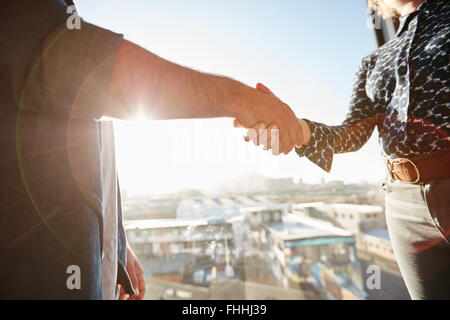 Handschlag von zwei Mitarbeitern mit Sonnenlicht. Männliche Führungskraft seine Hand mit Kollegin, Konzentration auf Hände zu schütteln. Stockfoto