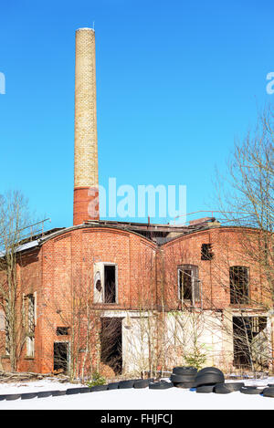 Einem verlassenen Fabrikgebäude mit einem hohen gemauerten Schornstein gegen blauen Himmel. Industriegebiet in Fridafors, Schweden. Stockfoto