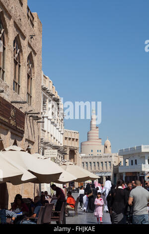 Menschen herumlaufen und Essen im Souq Waqif, Doha, Katar. Fanar in der Ferne. Stockfoto