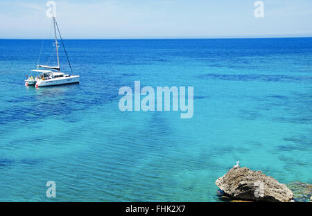 Mallorca, Balearen, Spanien: das kristallklare Wasser des Mittelmeers und ein Katamaran Segeln in Cala Torta, abgelegenen Strand im Norden Stockfoto