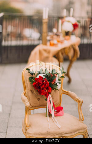Schöne Hochzeit Bouquet mit roten Blüten auf dem Vintage Beige Stuhl Stockfoto