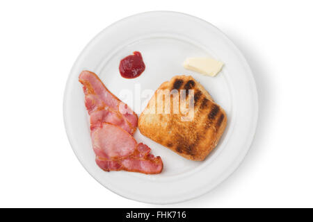 Zwei Speckscheiben Speck und eine Scheibe Toast auf einem Teller mit Butter und Tomaten Ketchup auf einem weißen Hintergrund Stockfoto