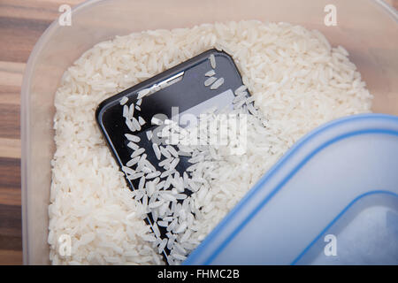 Verwendung von ungekochtem Reis, ziehen Feuchtigkeit von einem Mobiltelefon. Stockfoto