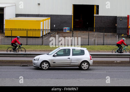 Zwei Radfahrer tragen rote Jacken und Schutzhelme auf ihren Fahrrädern entlang der Kingsway Schnellstraße in Dundee, Großbritannien Stockfoto