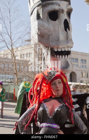 Eine riesige Schädel Marionette grins toothily hinter einer Frau, gekleidet in einem bunten Kostüm in Asheville Karneval parade Stockfoto