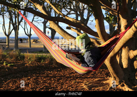 Montpellier, Languedoc-Roussillon, Frankreich. 25. Februar 2016. Winter-Sonnenuntergang über dem Peyrou Gärten. Ein junger Mann genießen die letzten Sonnenstrahlen zu widmen, um lesen. Bildnachweis: Digitalman/Alamy Live-Nachrichten Stockfoto