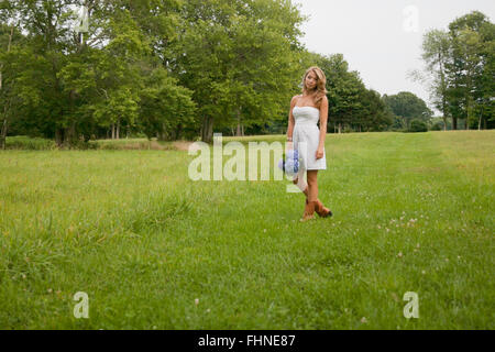 Schöne blonde Frau in einer Wiese wartet auf jemanden Stockfoto