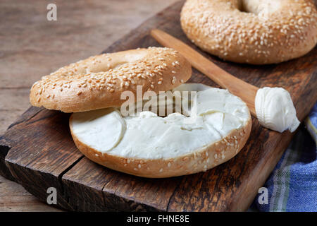 Bagel mit Frischkäse auf Holztisch Stockfoto