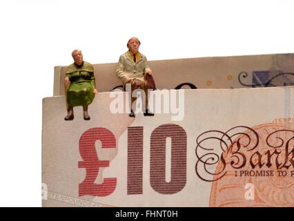 Zwei Miniatur Alter Rentner sitting on Top of British 10 und 20 Pfund Noten Stockfoto