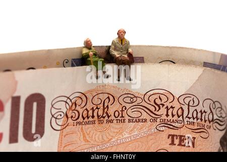 Zwei Miniatur Alter Rentner sitting on Top of British 10 und 20 Pfund Noten Stockfoto