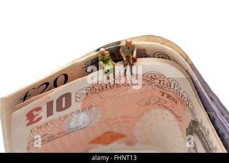 Zwei Miniatur Alter Rentner sitting on Top of British 10 und 20 Pfund Noten Stockfoto