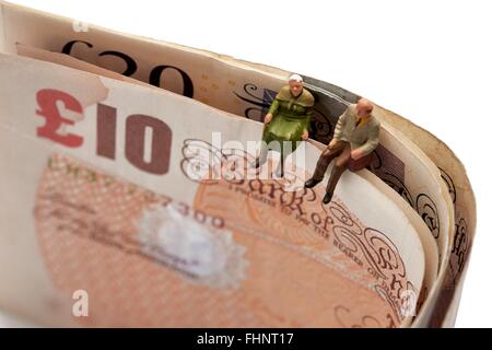 Zwei Miniatur Alter Rentner sitting on Top of British 10 und 20 Pfund Noten Stockfoto