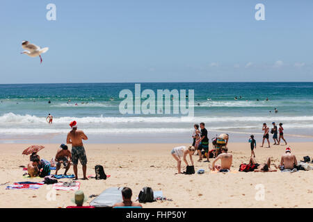 Heiligabend am Manly Beach, Sonnenanbeter mit Santa Hüte. Stockfoto