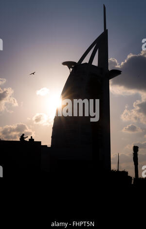 Dubai, Vereinigte Arabische Emirate - 2. Dezember 2014: Blick auf den Burj Al Arab Silhouette und Touristen in der Abenddämmerung. Blick vom Strand von Jumeirah. Stockfoto