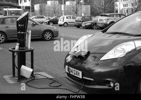 Neue Nissan Leaf Elektroauto angeschlossen und aufgeladen, während auf einem Parkplatz (Parkplatz) Stockfoto