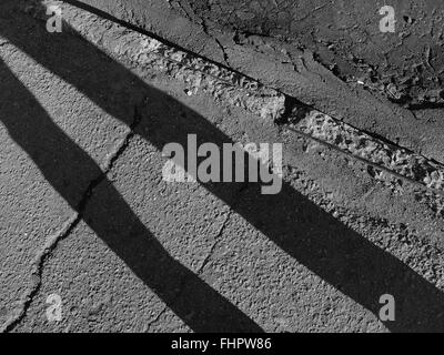 Diagonale Schatten auf dem gebrochenen Asphalt Bürgersteig und Grenze Stockfoto