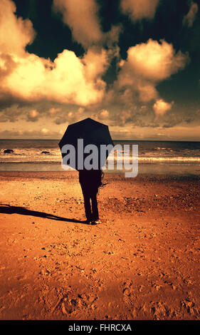 Frau mit Sonnenschirm am Strand Stockfoto