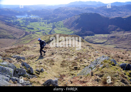 Einsame Dame zu Fuß nach unten in Richtung Grasmere von der Oberseite des Sitzes Sandale im Lake District Stockfoto