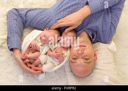 Vater liegen auf einem Flokati hält seine eineiigen Zwillingen von 3 Wochen alt Stockfoto