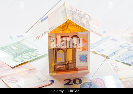 Haus von Euro-Banknoten auf einem weißen Holzboden Stockfoto