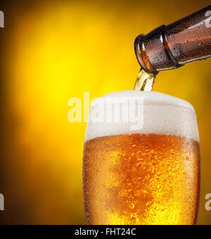 Der Prozess der strömenden Bier in das Glas. Leuchtend orange Hintergrund. Stockfoto