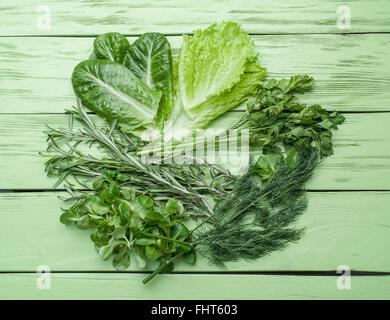 Grüne Kräuter auf dem grünen hölzernen Hintergrund. Stockfoto
