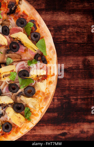 Bunte Pizza auf dunklem Holz. Stockfoto